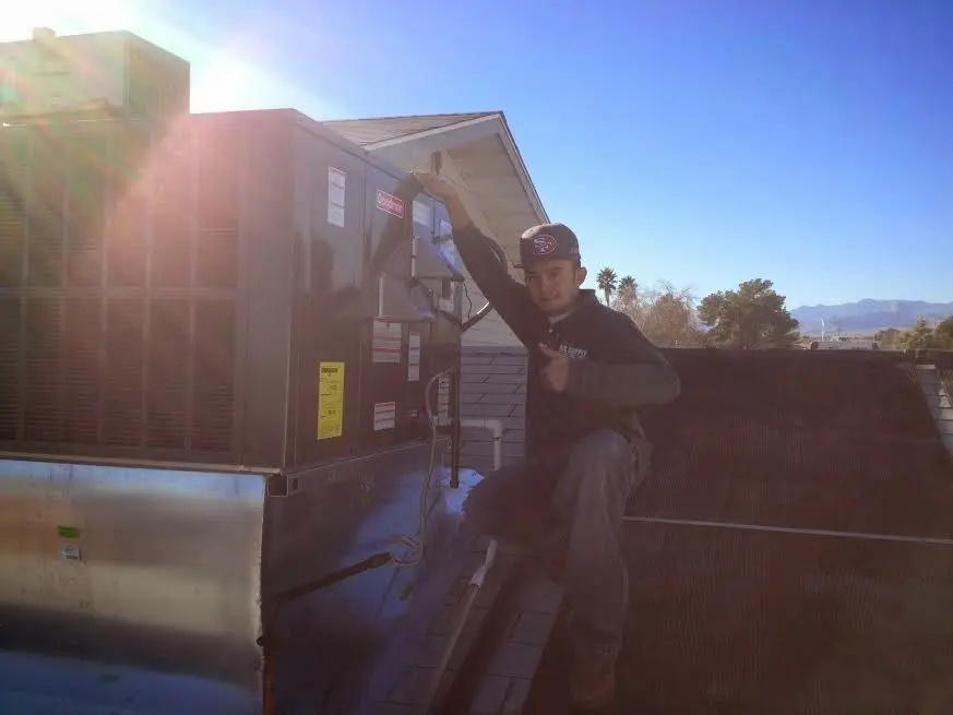 HVAC technician performing Air Duct Cleaning on a rooftop unit in Rochester